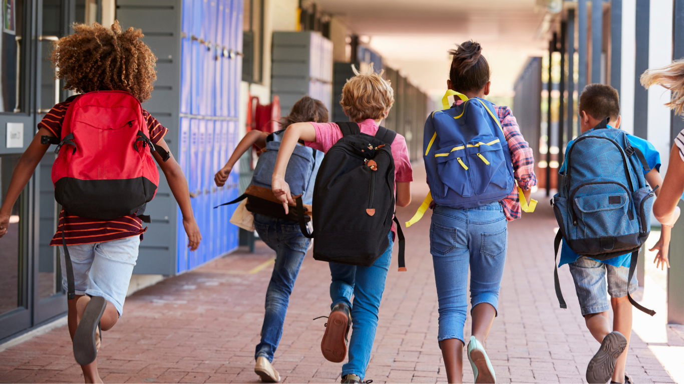 Kinder in der Schule mit Schultasche am Rücken