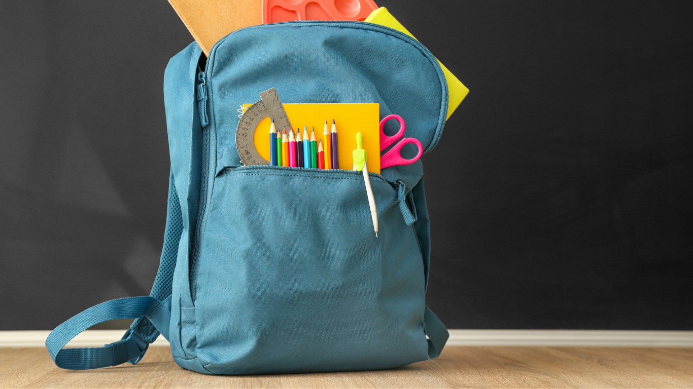 eine blaue Schultasche mit Bücher, Stifte und Schere
